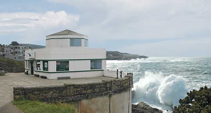 modular building perched above ocean with crashing waves