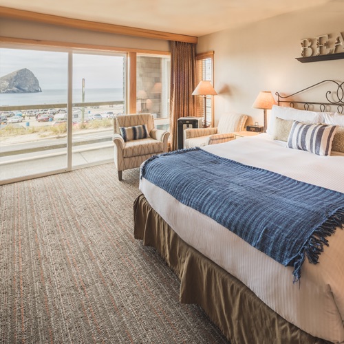 hotel room with large bed, carpeting and floor to ceiling windows with scenic ocean view