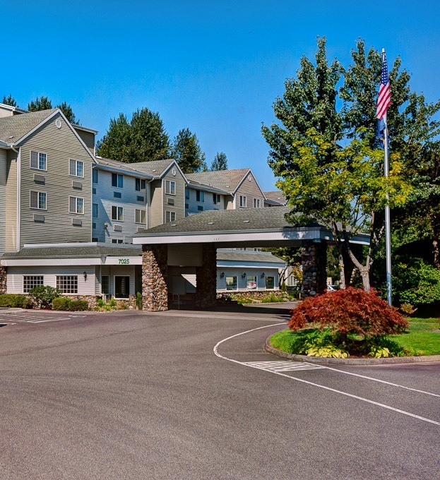 Hotel entrance with flag, trees, and parking area.