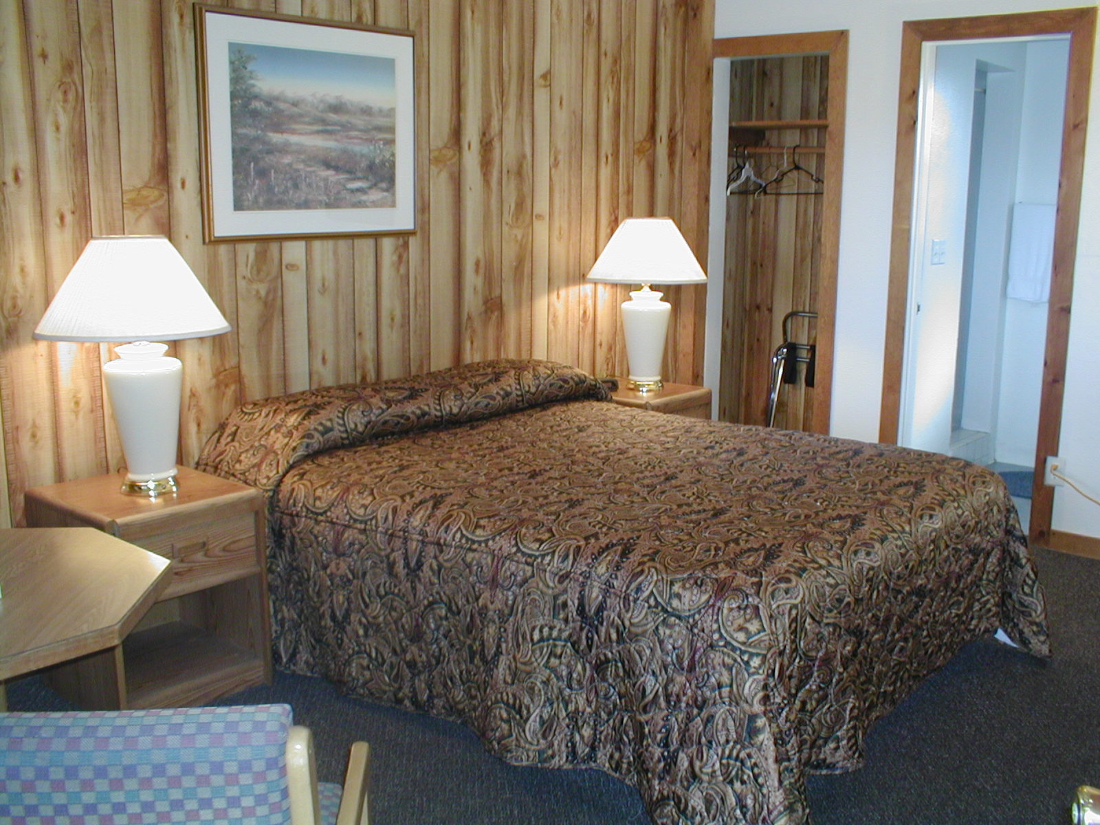 motel room with wood panelling, double bed and wooden nightstands with a lamp on each