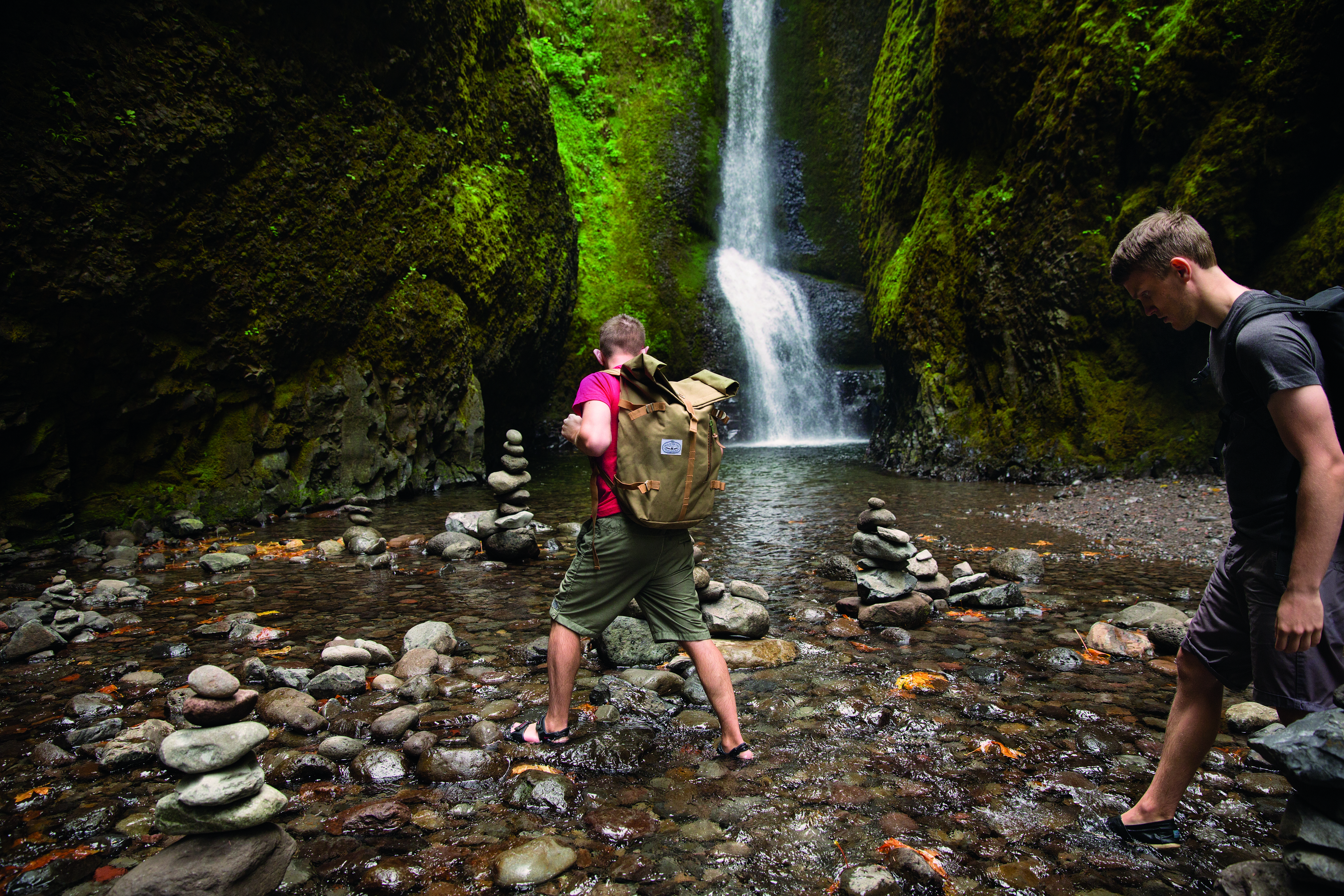 Two hikers walking near a waterfall.