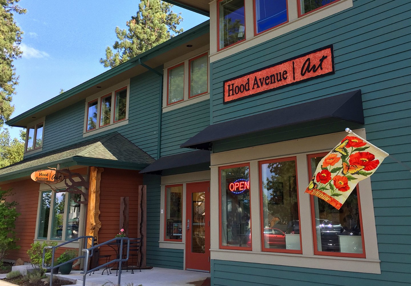Hood Avenue Art shop with open sign and flowers.