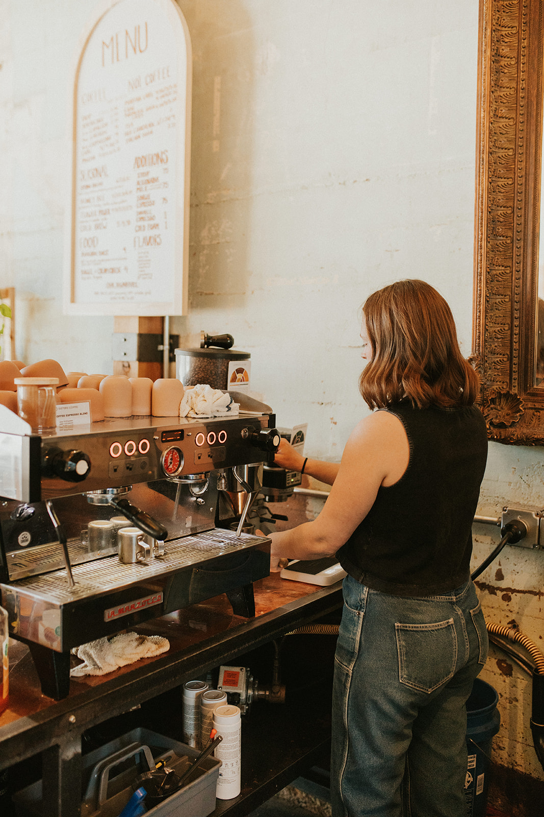 Girl in black top making espresso at Golden Coffee with an industrial espresso maker