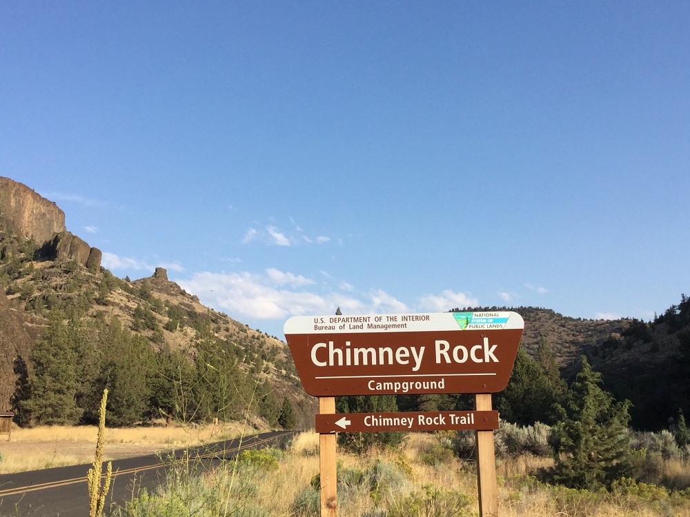 "Chimney Rock Campground sign with mountains in background."