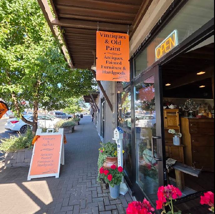 A sidewalk view of a shop called “Vintiques & Old Paint,”
