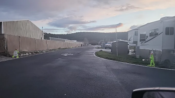 Parking lot at dusk with vehicles and a fence on the right