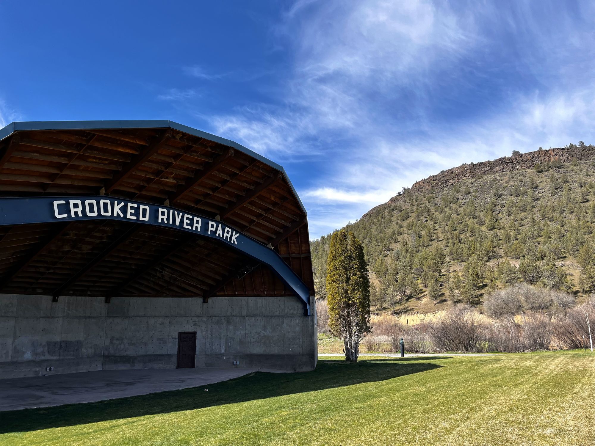 outdoor amphitheater with green grass and a hill with trees in the background