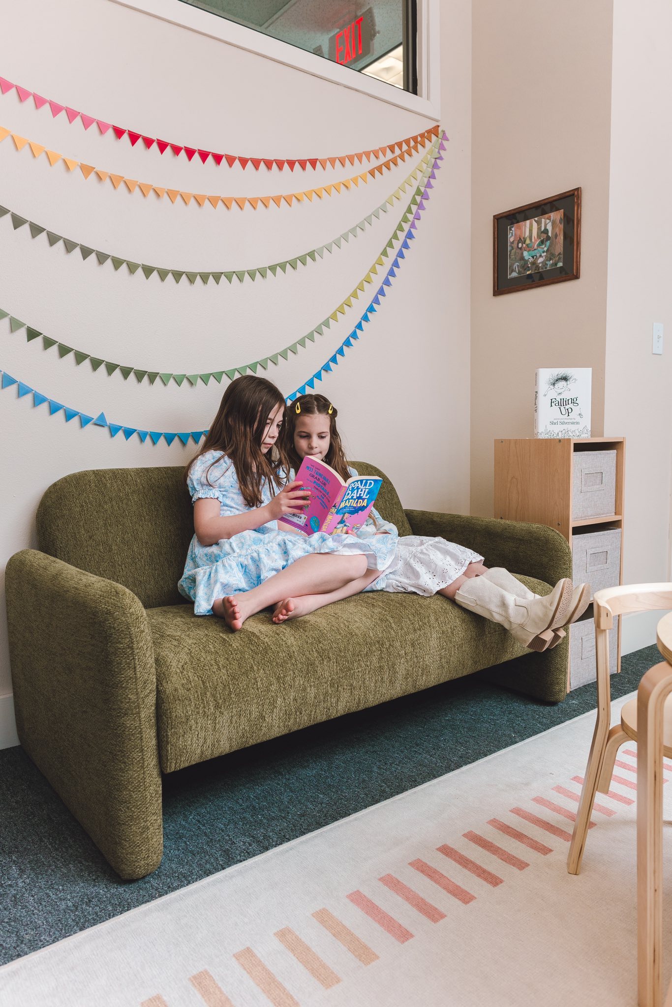 Two girls in dresses reading books on a couch in Prineville, Oregon at Oliver Books