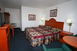 Bedroom with bed, lamps, table, and TV.