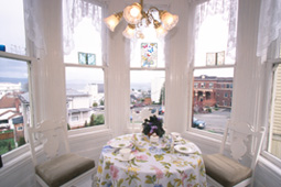 table with two chairs under a pendant lamp surrounded by windows with view of city streets and buildings