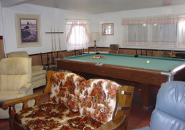 Living room with a pool table, chairs, and artwork.
