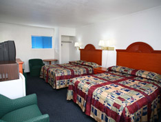 Hotel room with three beds and a chair.