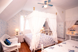 guest room with a canopy bed, regular twin bed and wicker loveseat
