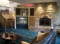 Living room with fireplace, large TV, and leather couch.
