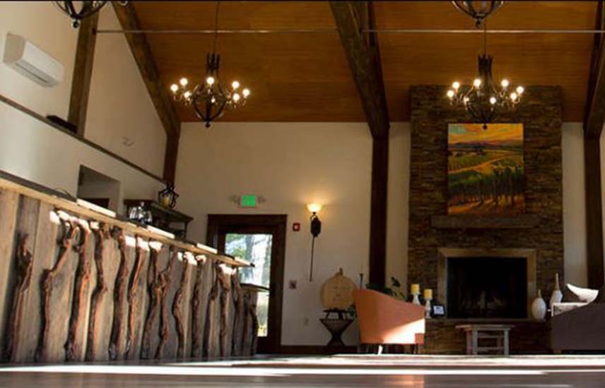 interior of winery tasting room with exposed wood ceilings, modern fixtures and fireplace