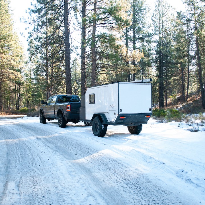 truck pulling camper trailer on snow covered road