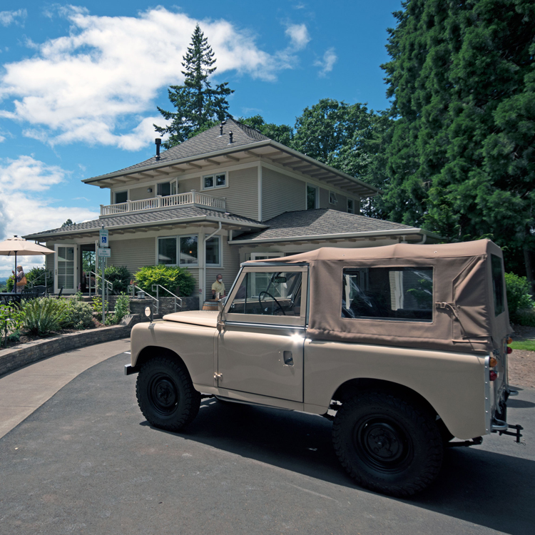 vintage land rover parked near two story four square home