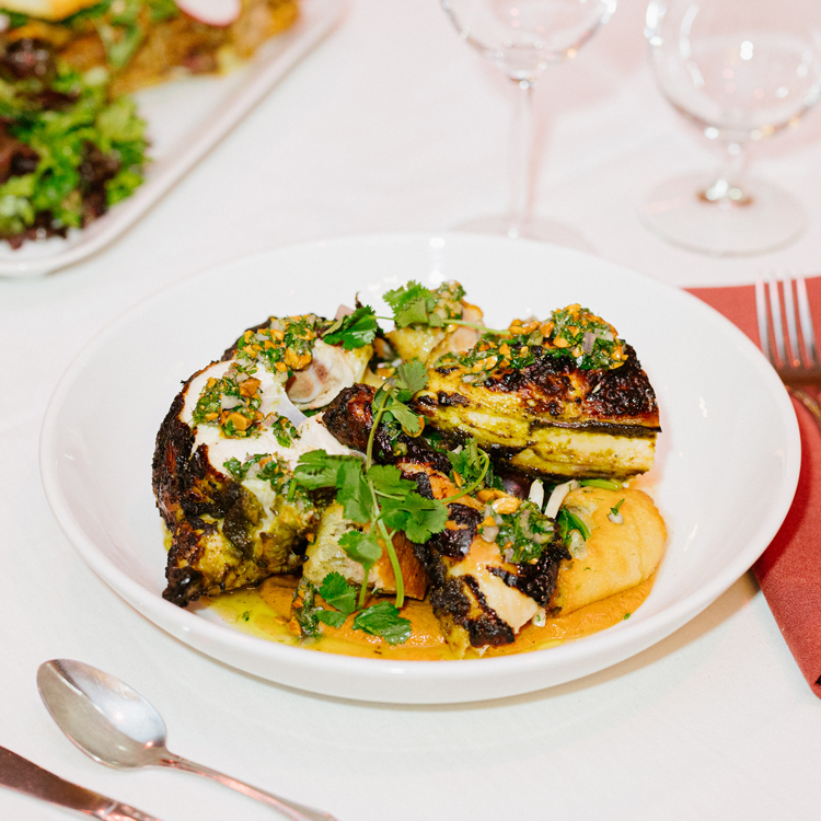 fine dining entree on bowled plate surrounded by elegant table setting