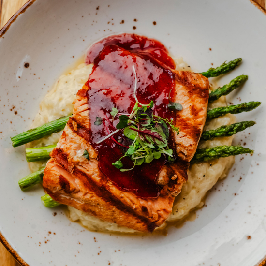 entree plate with fish over asparagus and a mashed vegetable
