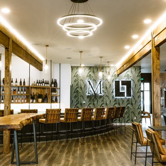 interior of wine tasting room with high bar, high stools, tables and chairs, exposed wood beams