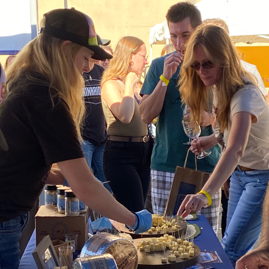 two people taste cheese samples at vendor booth