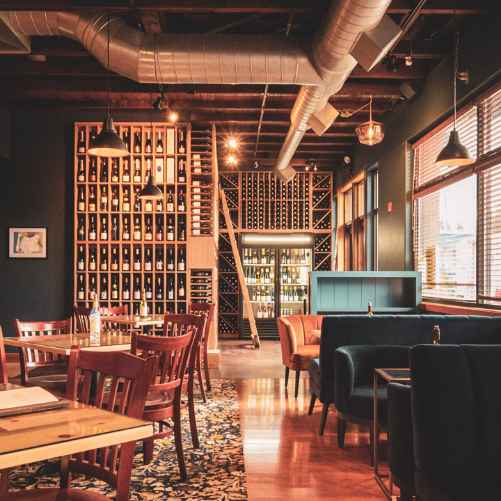 dining area of wine bar with wooden tables and chairs, booth seating and walls of wine bottle storage