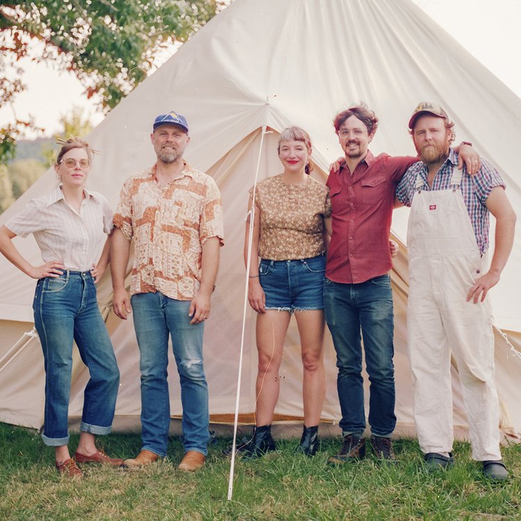 five people standing in front of tall tent