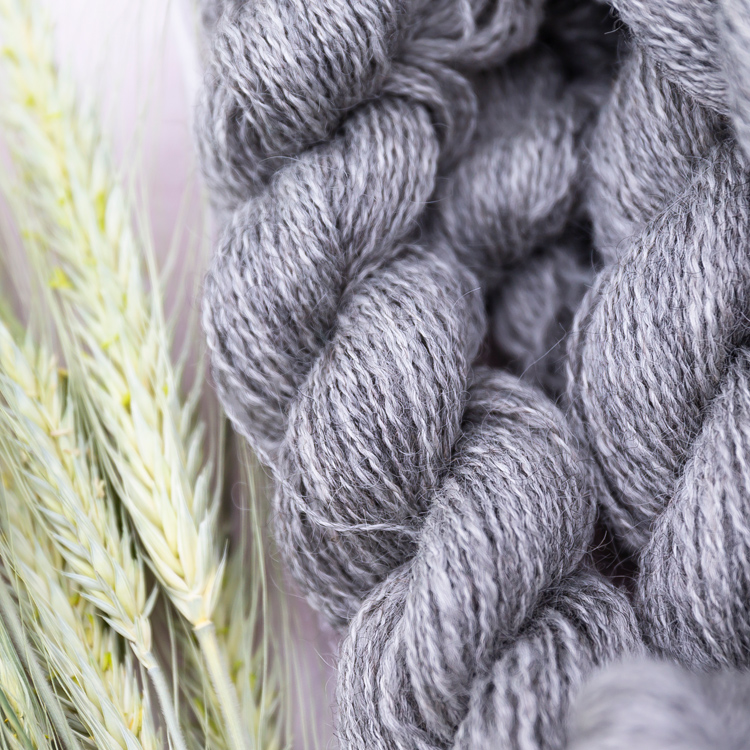 skein of yarn next to four straws of wheat