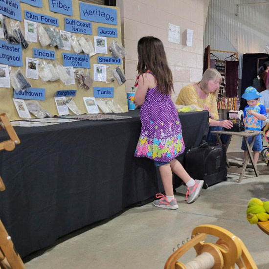 child looks at samples at a fiber market show