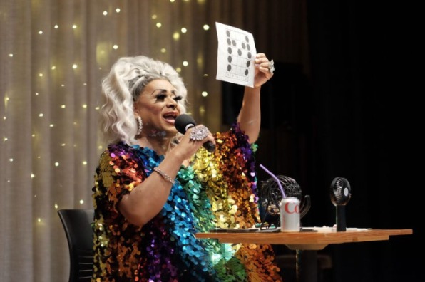 Bingo caller dressed in multicolored sequin outfit.