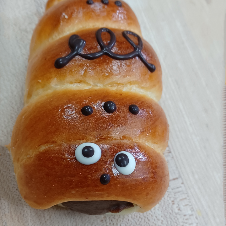 chocolate filled bread roll with googly eyes and nose decorated on it. The filling is the mouth