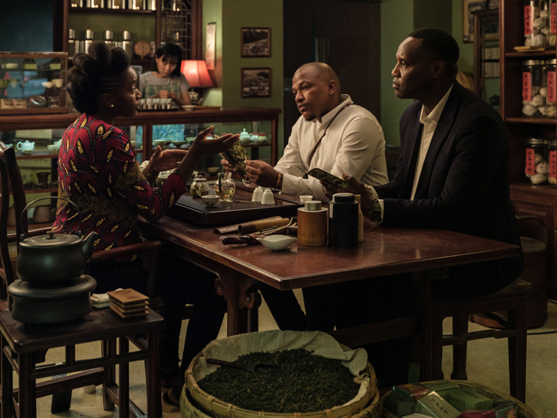 still from film entitled Black Tea; Three people seated at a table in a tea shop