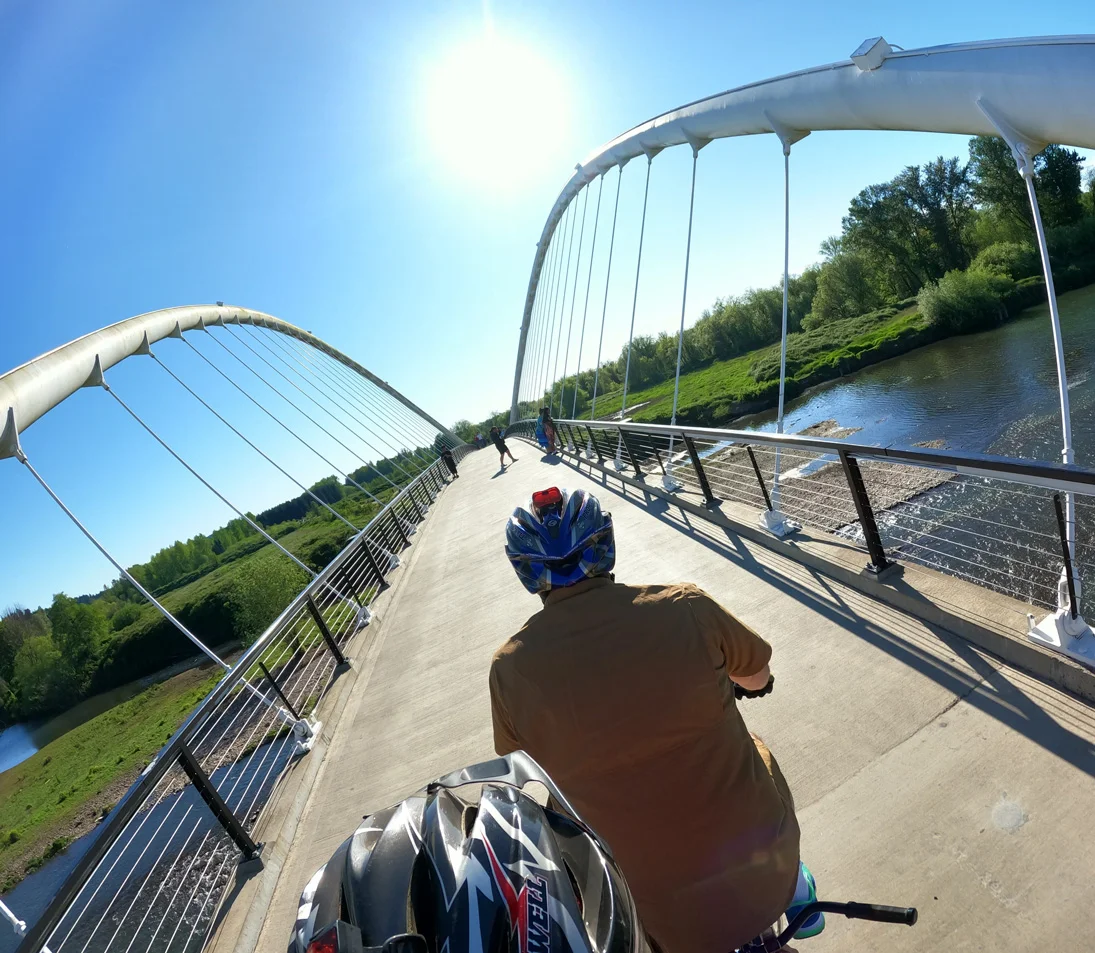 Tandem cyclists pedal over a bridge.