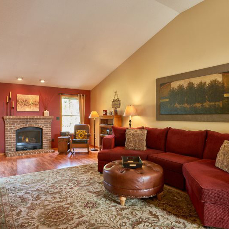 large living room with brick fireplace and sectional couch with leather footstool