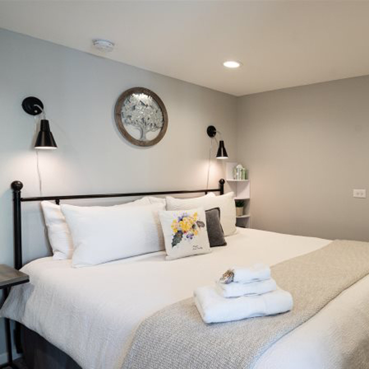 bedroom with large bed with metal bed frame, night stand and wall lamps