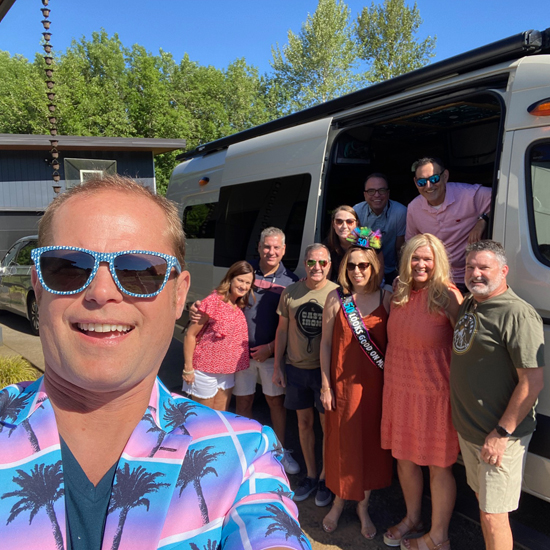 person takes selfie with group standing outside of sprinter van