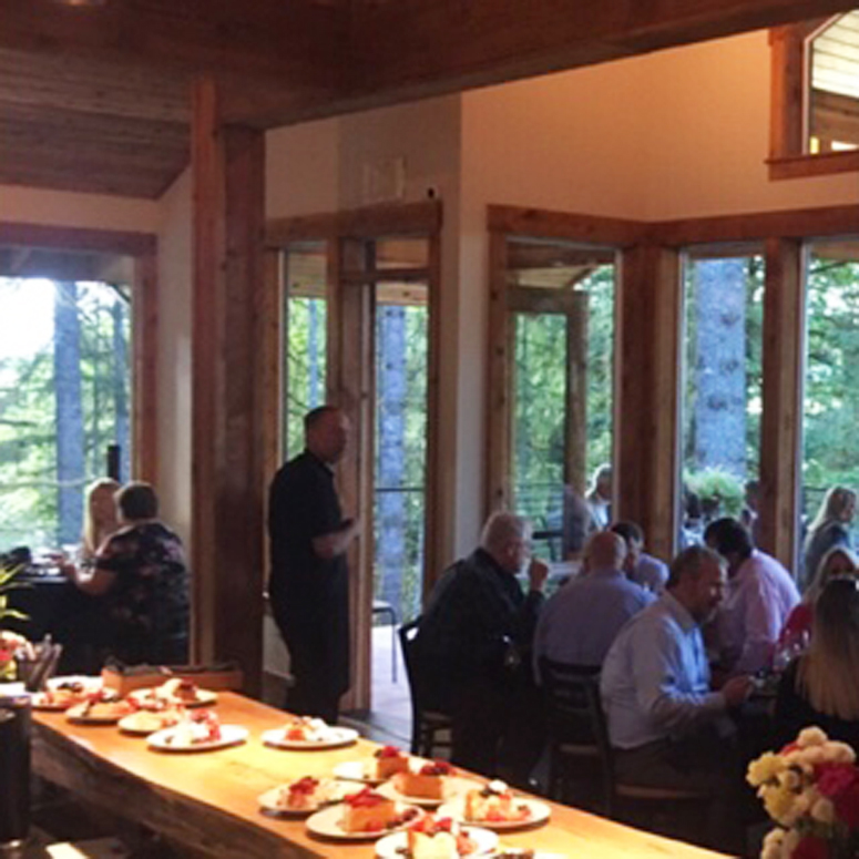 Dining room with people seated around tables and desserts on a long table.