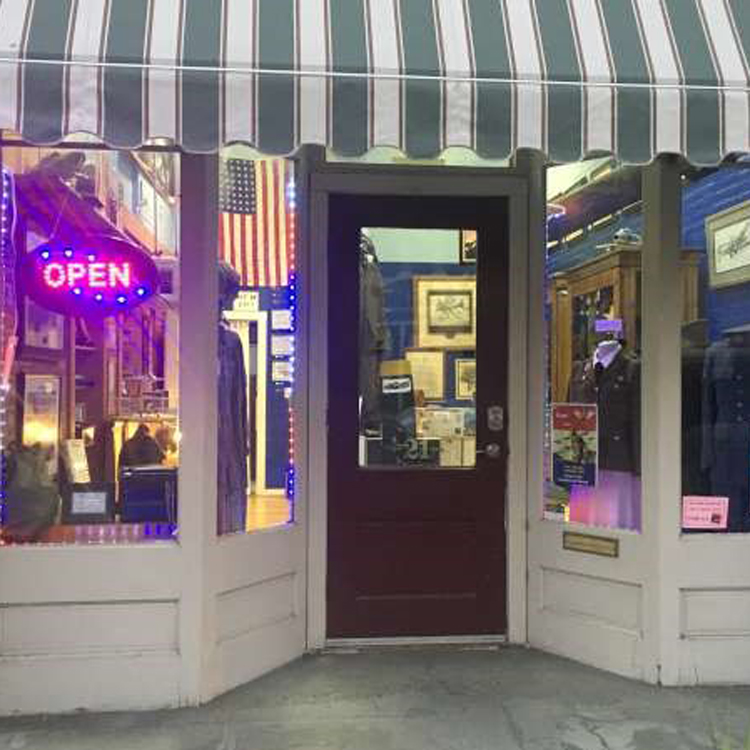 museum storefront with striped awning, two large windows on either side of door with large window