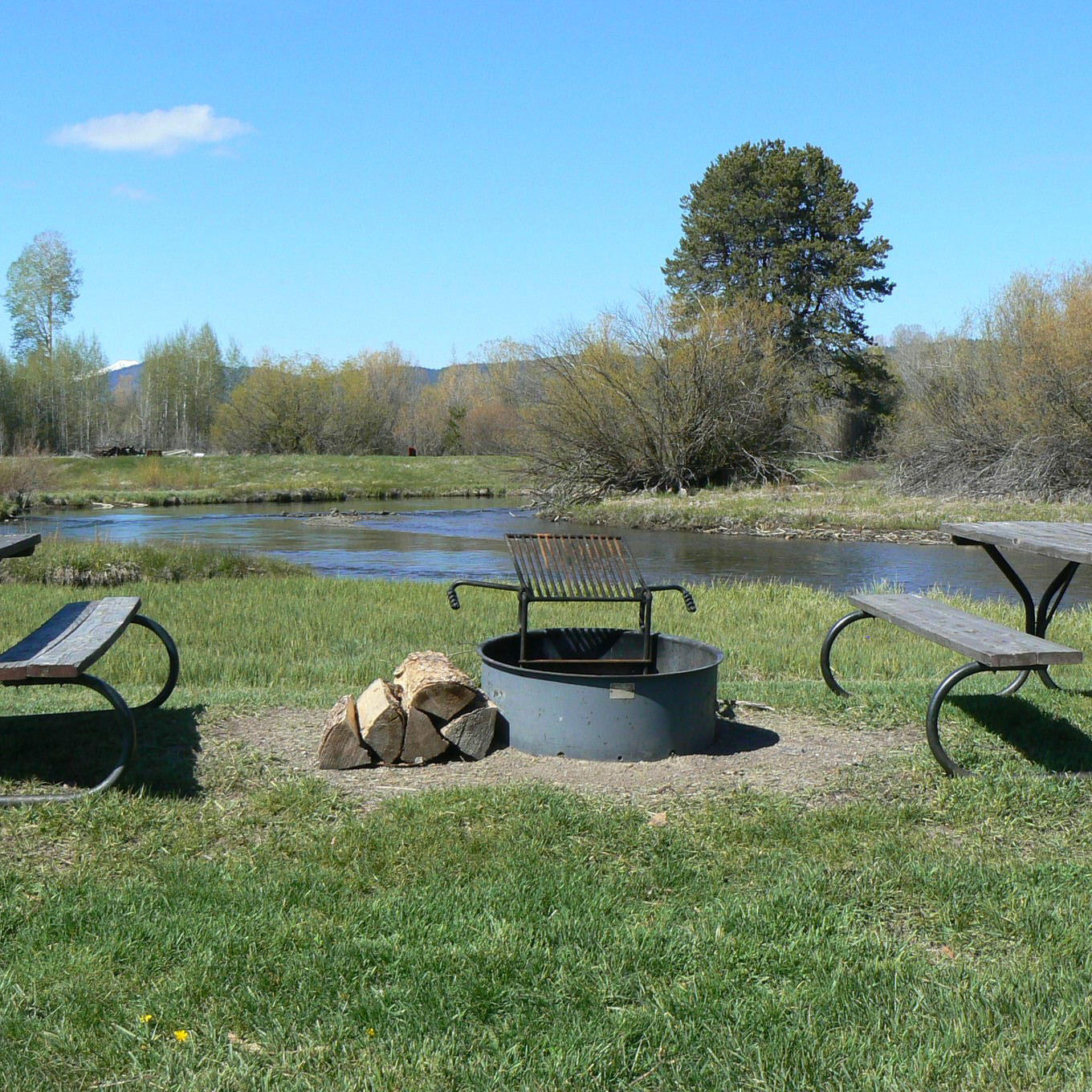 campsite on river with two picnic tables and a fire ring