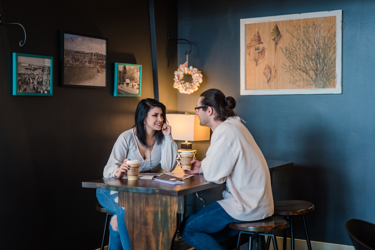 two people sit across from each other at rustic table in cafe