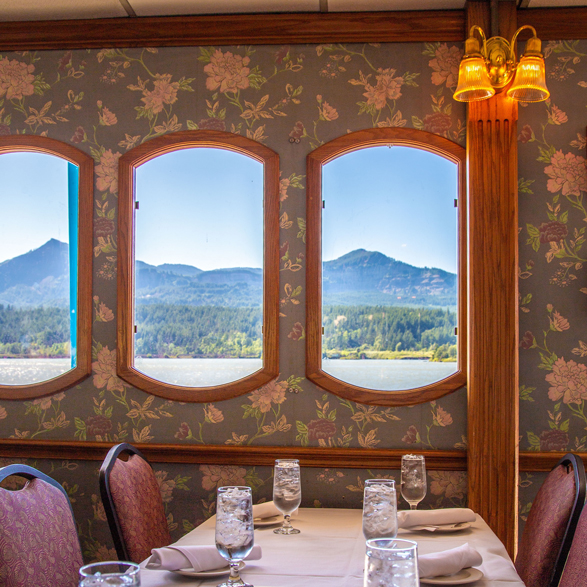 river and mountain views through the windows of dining room of riverboat