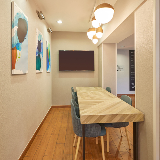 table and chairs in narrow space with art on wall