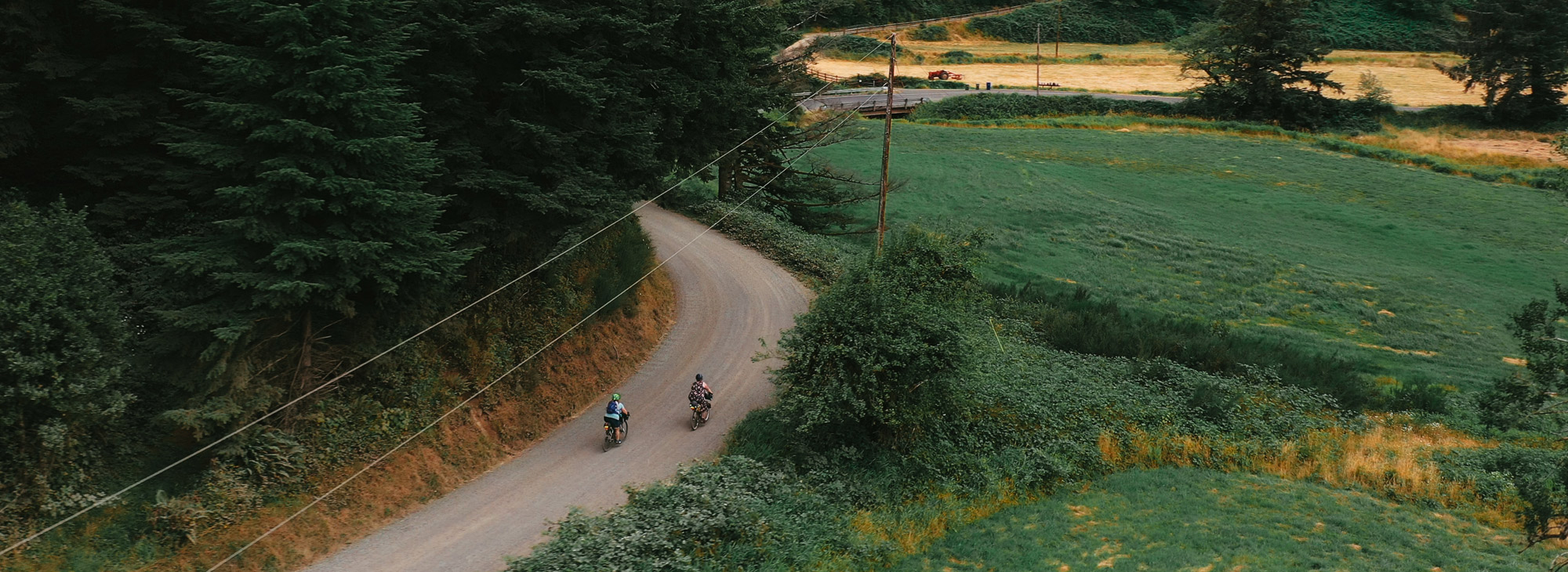 two bicyclists riding gravel route through farmland