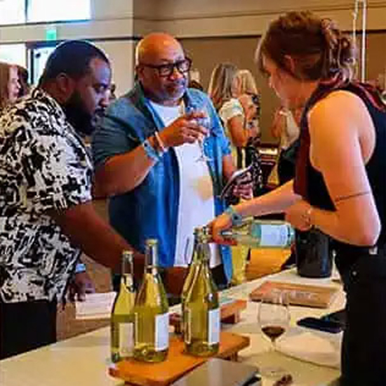 two people tasting wine at a vendor booth of a wine tasting event