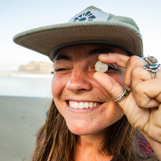 person holds tiny sand dollar in front of their eye