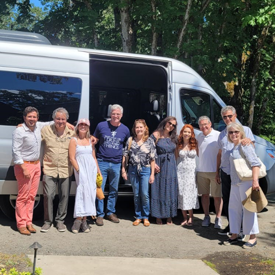 ten people smile in front of Sprinter van