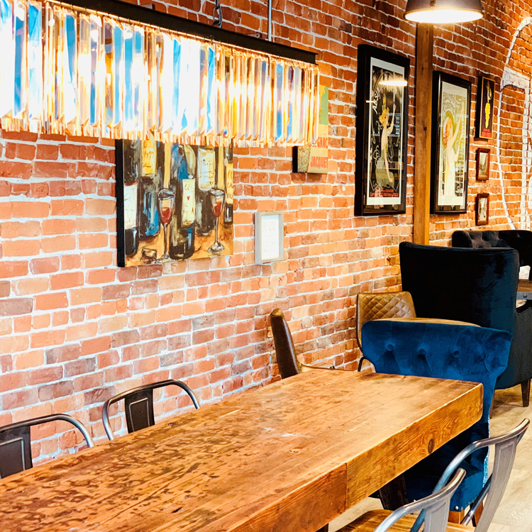 long wood table surrounded by metal chairs in brick wall