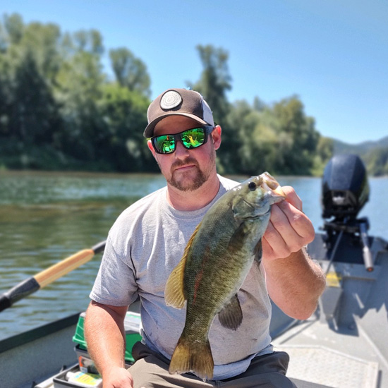 man wearing sunglasses holds up fish