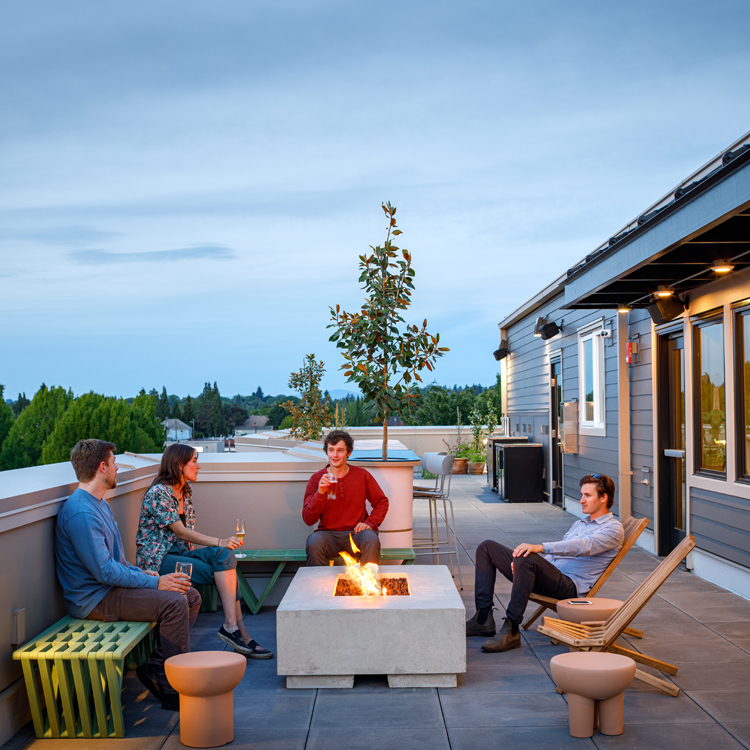 four people seated around fire pit on outdoor rooftop patio