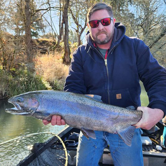 man wearing sunglasses holds large fish that he caught